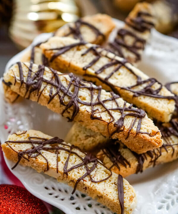 A white serving plate with a pile of Chocolate Almond Biscotti stacked on top.