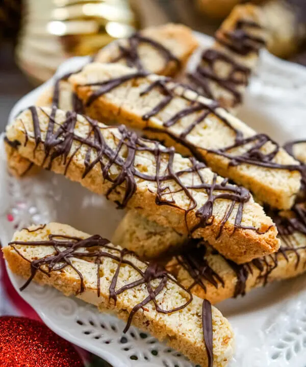 A white serving plate with a pile of Chocolate Almond Biscotti stacked on top.