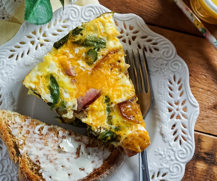 Ham, Asparagus, and Potato Frittata on a plate next to buttered toast and juice.