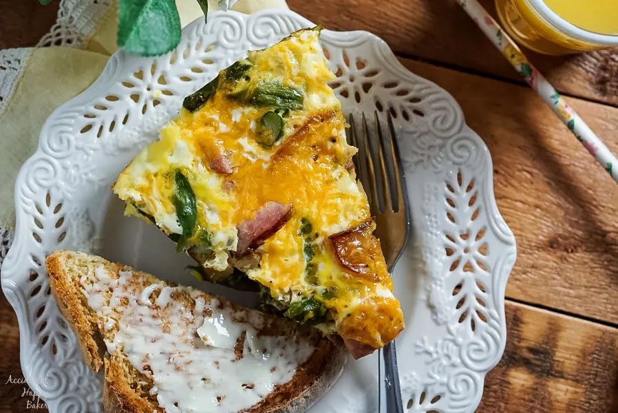 Ham, Asparagus, and Potato Frittata on a plate next to buttered toast and juice. 