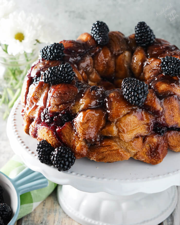 A white platter with Blackberry Monkey Bread on top and several blackblack berries surrounding it. 