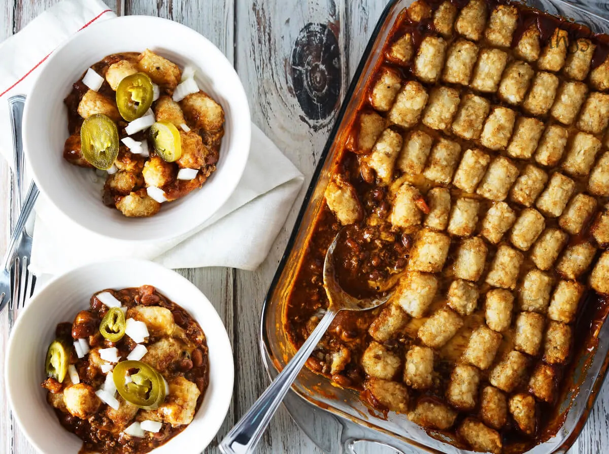 Two servings of Chili Cheese Tater Tot Casserole next to a casserole pan. 