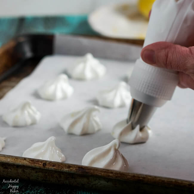 Piping star shaped lemon meringues onto the baking sheet. 