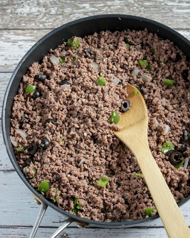Ground beef is cooked with onion, bell pepper, and black olives. 