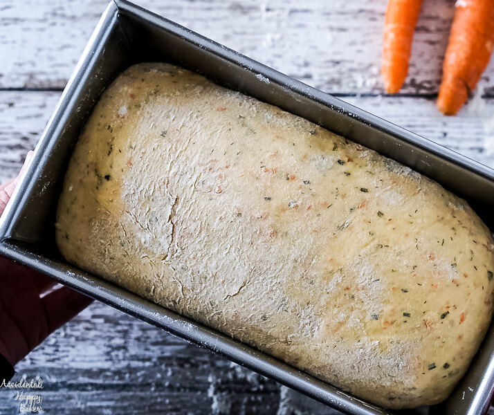 The carrot and chive bread dough is shaped into a loaf and placed in the bread pan for the final rise. 