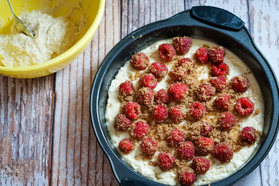 Raspberries and brown sugar are sprinkled over the cake batter. 