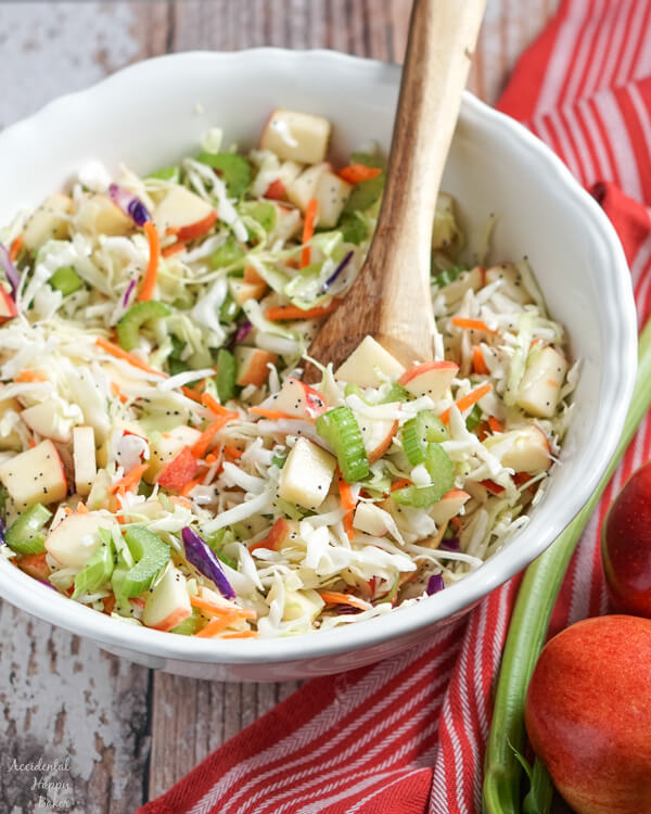 A large white serving bowl full of apple coleslaw. 