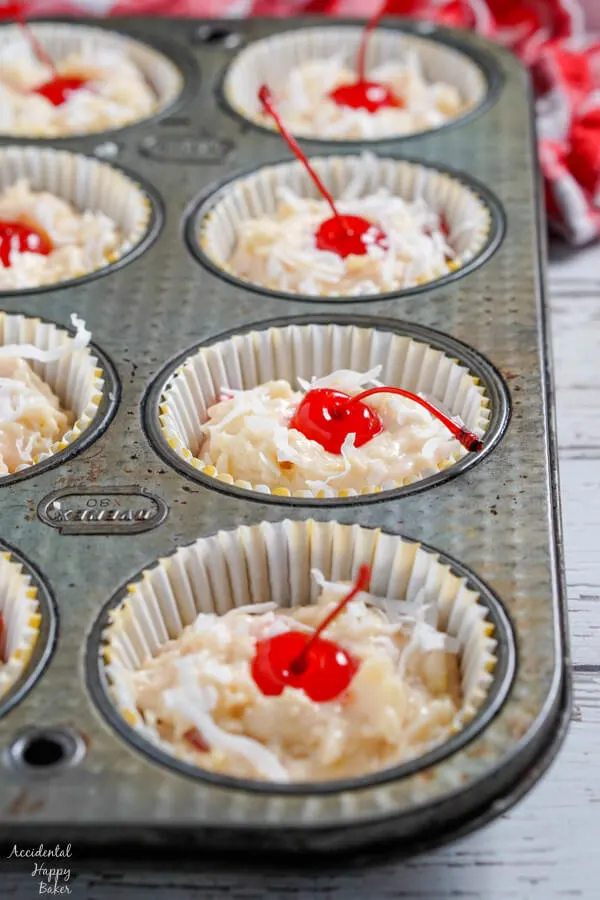 Maraschino cherries and coconut is pressed into the top of the muffins before baking. 
