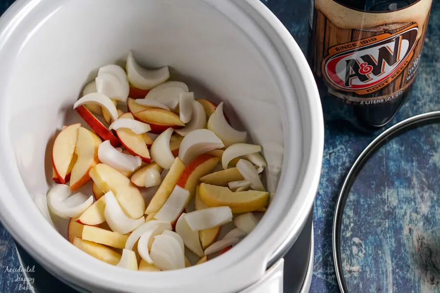 Sliced apples and onions are layered in the bottom of the slow cooker. 