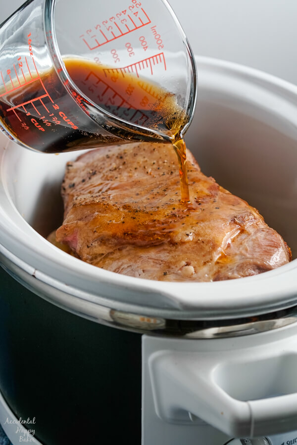 Root beer is poured over the pork, apples and onions into the slow cooker.