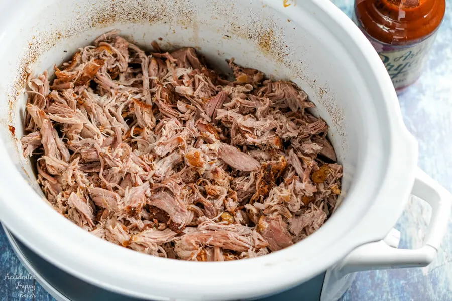 After slow cooking, the pork is shredded and returned to the slow cooker. 