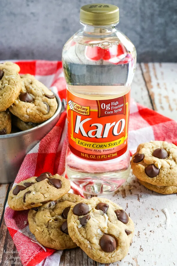 A stack of coconut chocolate chip cookies sits next to a bottle of Karo Corn Syrup