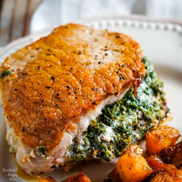 A close up image of a pork chop stuffed with a cheesy spinach filling. 