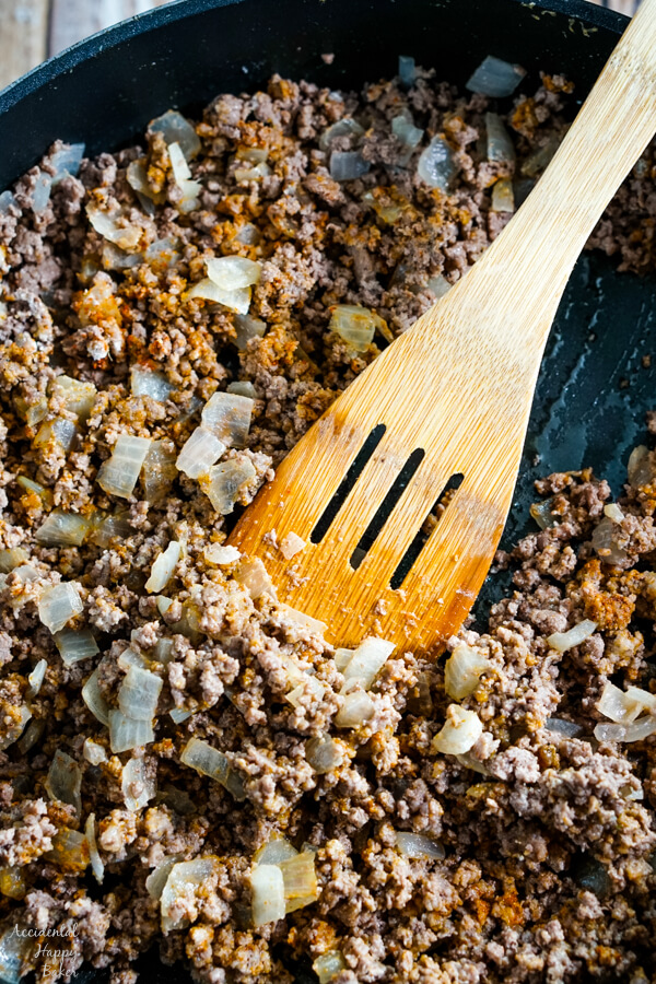 The seasonings are added to the ground beef in the pan. 