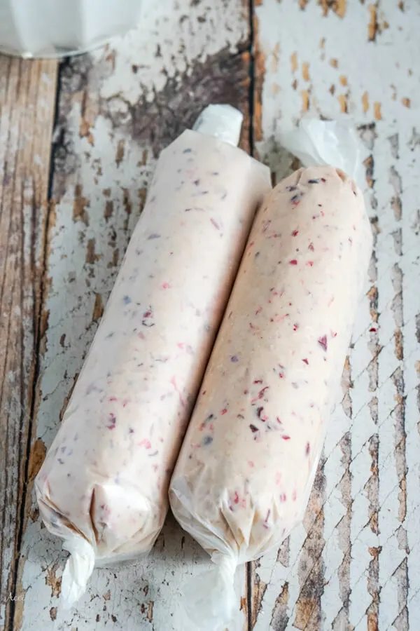 Two logs of cookie dough wrapped in waxed paper and ready to refrigerate. 