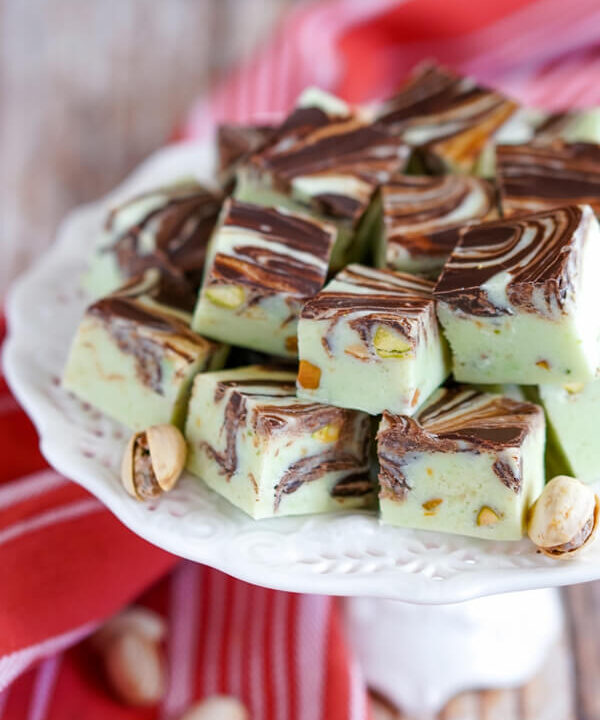 A white platter stacked high with Pistachio Swirl Fudge and pistachios.
