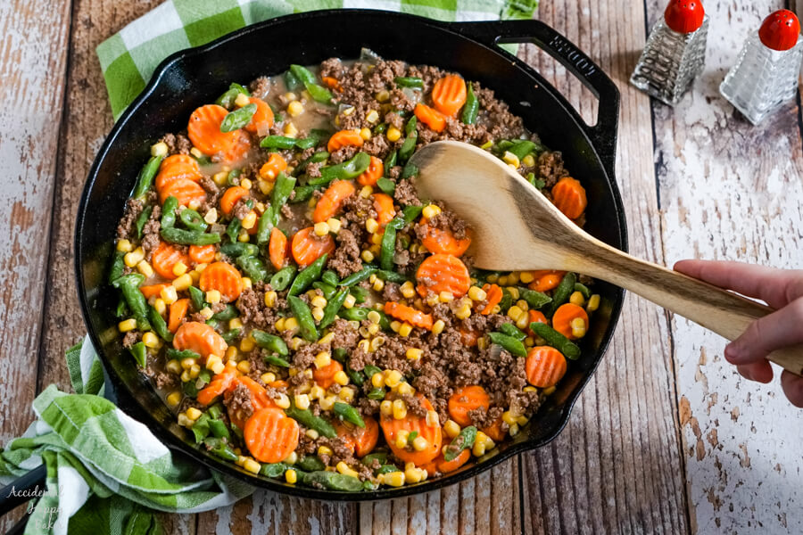 The mixed vegetables are added to the ground beef and sauce. 