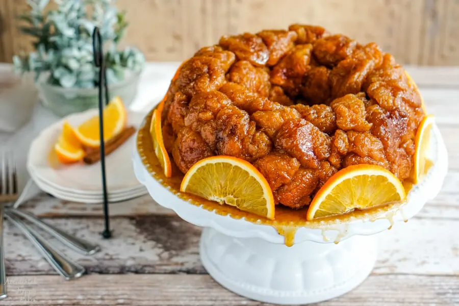 A plate of Orange Spiced Monkey bread beside a plate with sliced oranges. 