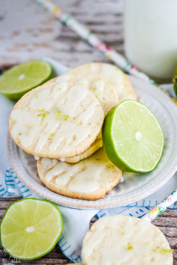 Key Lime Shortbread Cookies stacked on a white plate with slices of lime. 