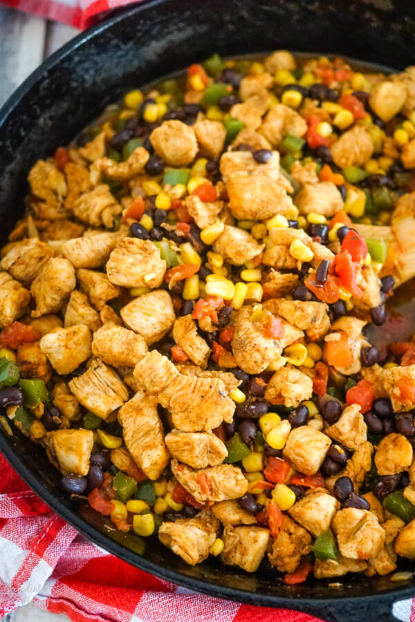 A cast iron skillet full of chicken and veggies. 