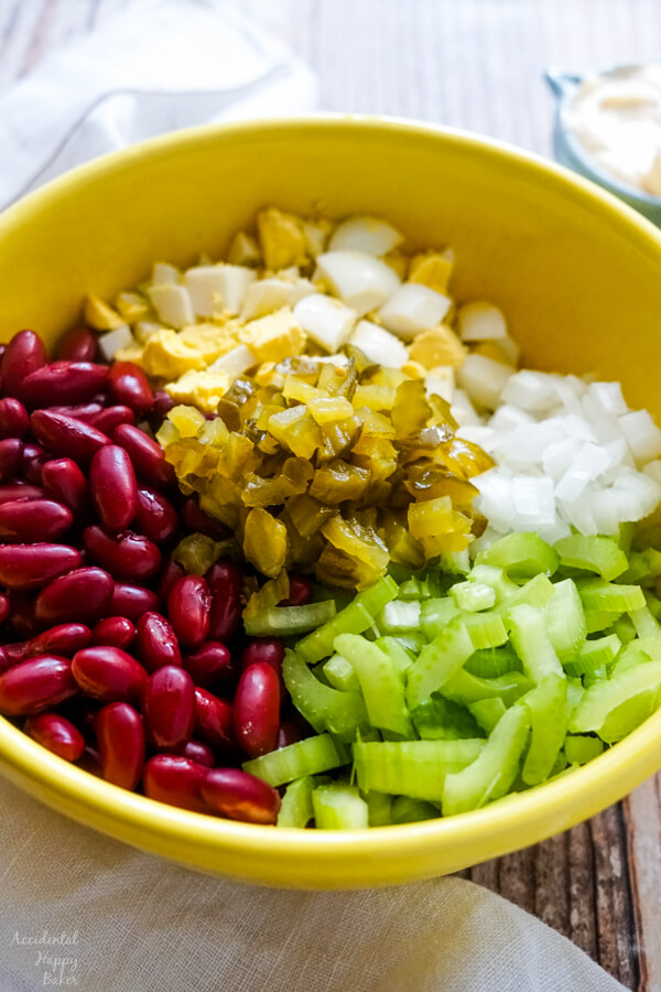 A yellow bowl full of the ingredients to make the salad before the dressing has been added. 