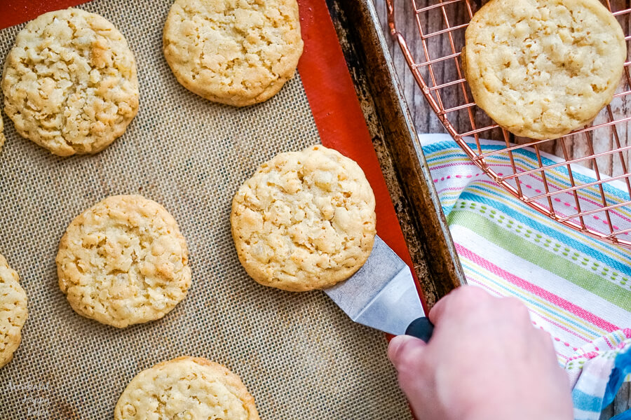 A sheet pan of freshly baked and cooled cookies with a spatula removing a cookie. 