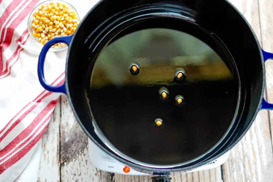 A few test kernels are added to the oil in the dutch oven. 
