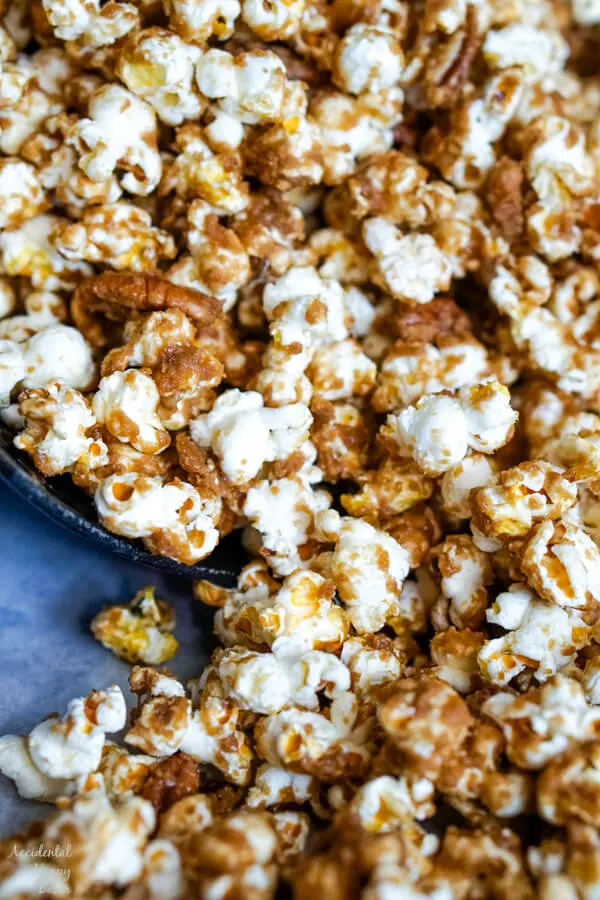 A close up image of the popcorn that shows the texture of the caramel on the popcorn and pecans. 