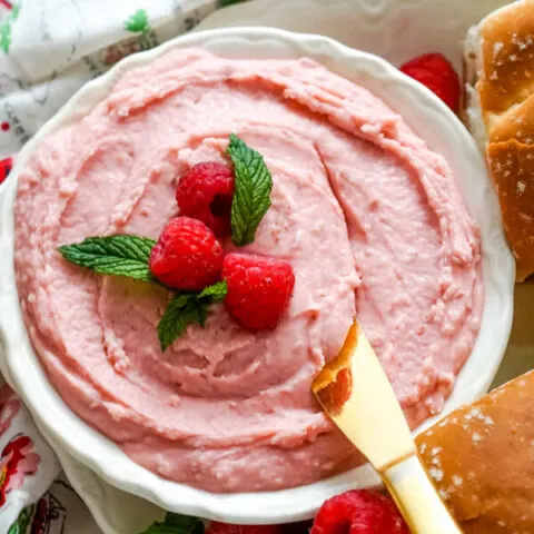A bowl of raspberry honey butter with a butter knife.