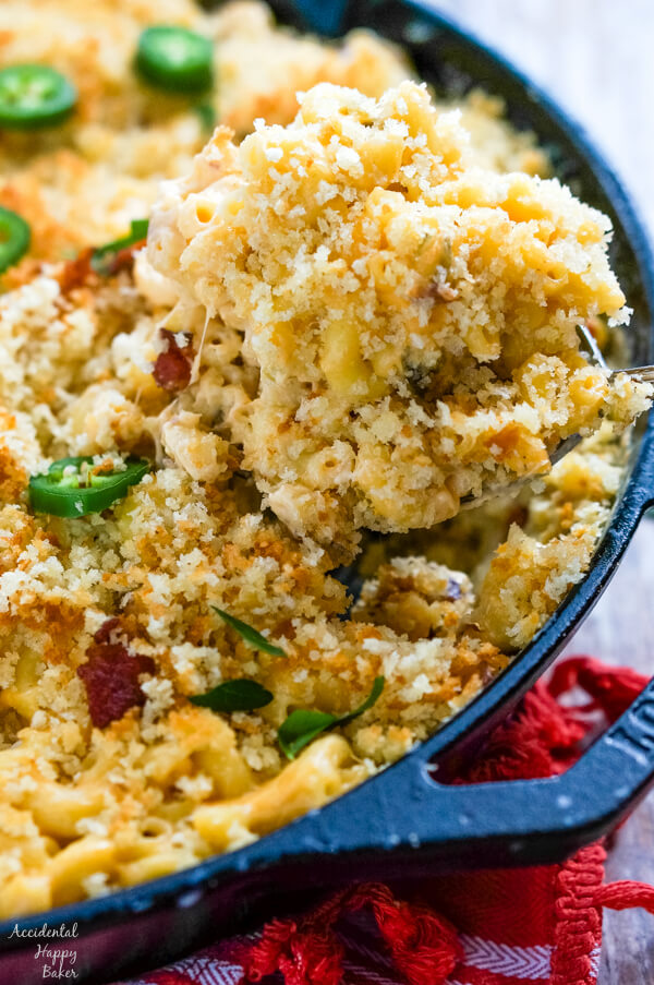 A serving of Jalapeno Bacon Mac and Cheese is removed from a cast iron skillet. 