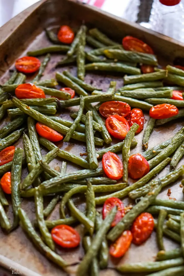 Green beans and cherry tomatoes on a sheet pan just after coming out of the oven. 
