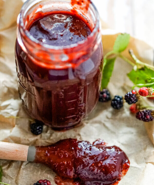 A jar of blackberry bbq sauce with a basting brush to one side.