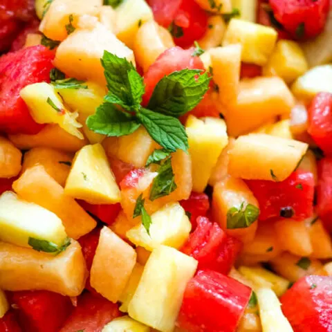 A close up image of watermelon fruit salad that shows the blend of watermelon, cantaloupe, pineapple, and fresh mint.