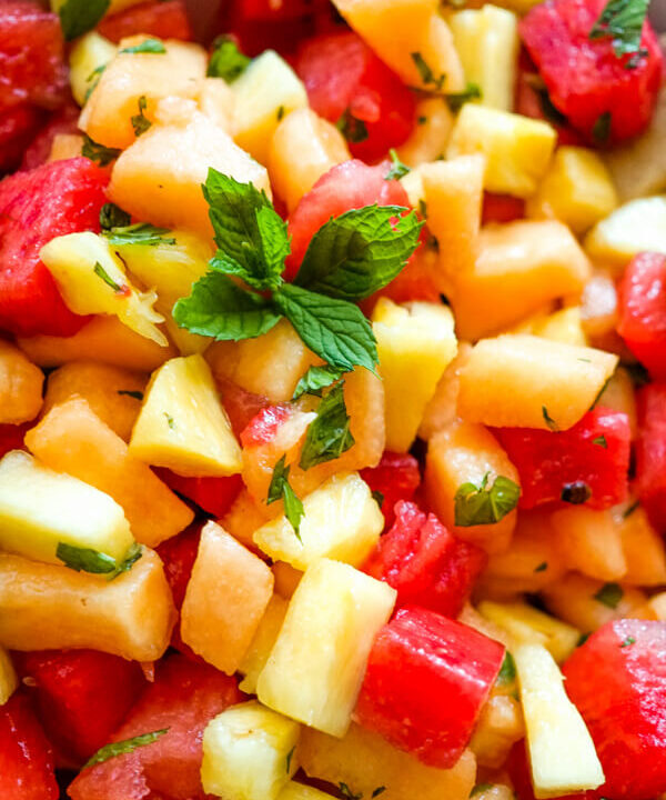 A close up image of watermelon fruit salad that shows the blend of watermelon, cantaloupe, pineapple, and fresh mint.