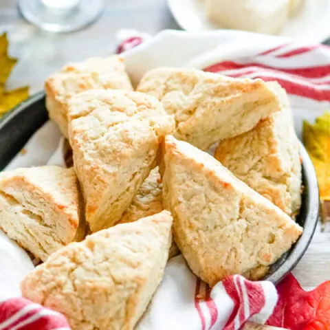 A pan full of white cheddar scones with a glass of wine in the background