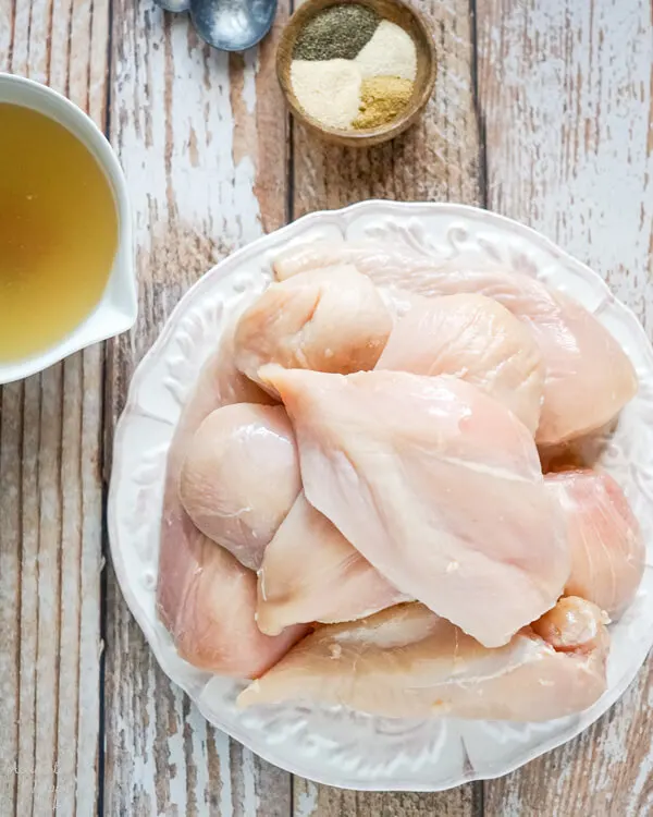A plate of trimmed fresh chicken breasts. 