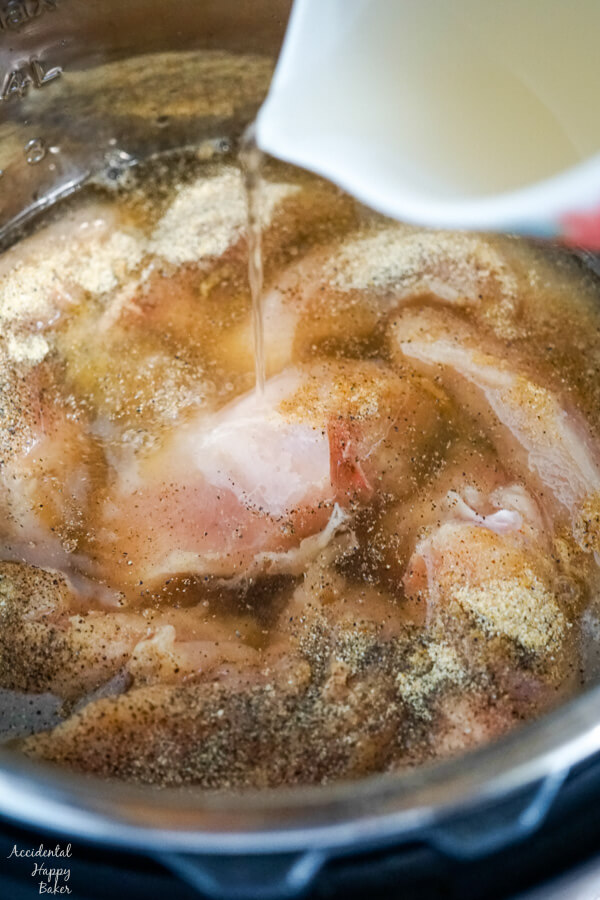 Chicken broth is poured over the seasoned chicken breasts.
