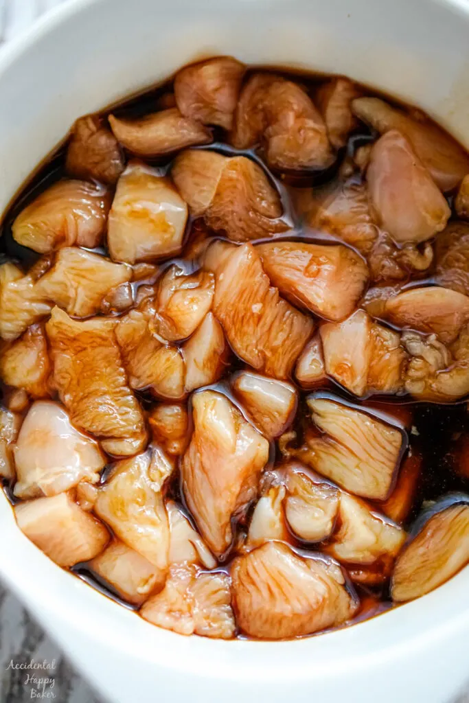 A bowl of chopped chicken soaking in the marinade. 