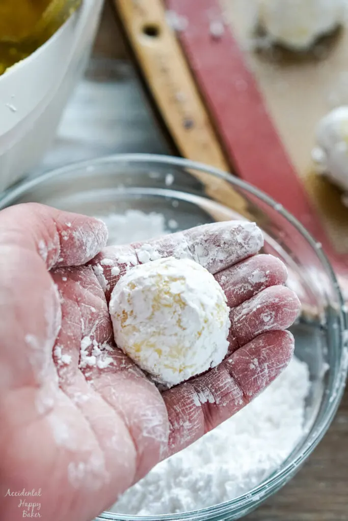 Step two, rolling the cookie dough into balls and then rolling the balls in powdered sugar. 