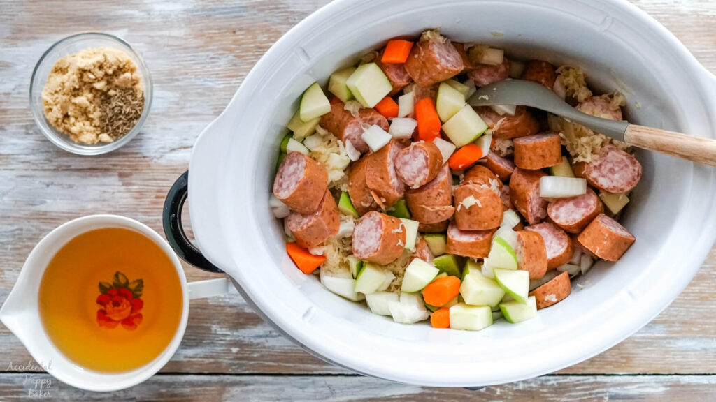 Sauerkraut, kielbasa and chopped veggies are added to the slow cooker. 