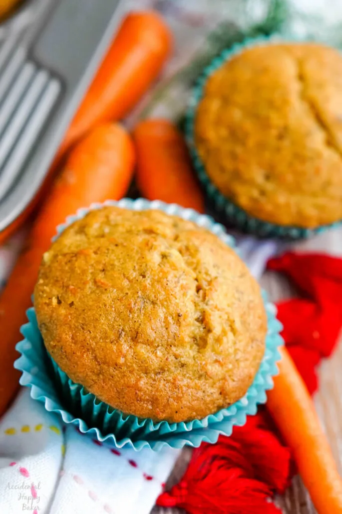 carrot banana muffin in cupcake liner with carrot beside it 