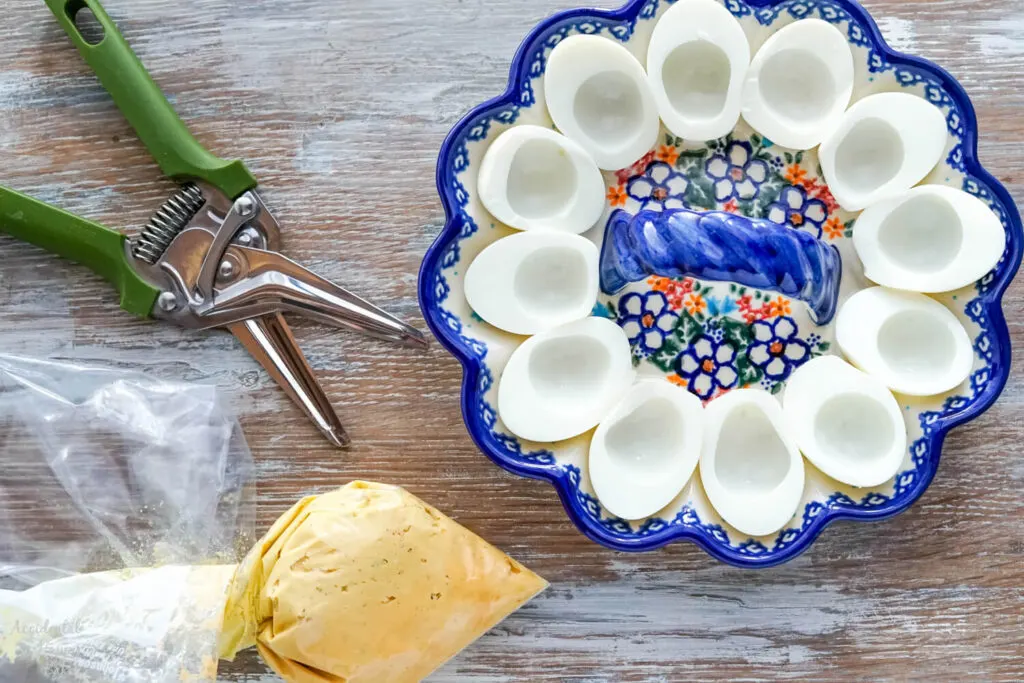 Filling ingredients in a Ziploc bag, and egg whites in a floral deviled egg dish.