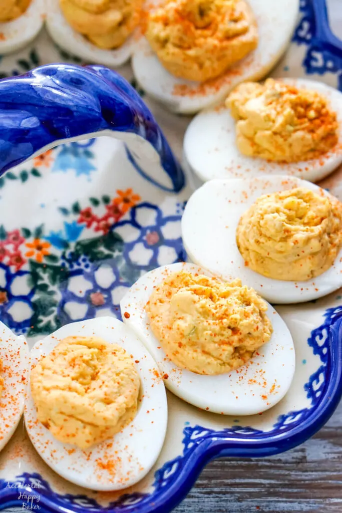 Spicy deviled eggs sprinkled with cayenne pepper nestled on a deviled egg dish. 