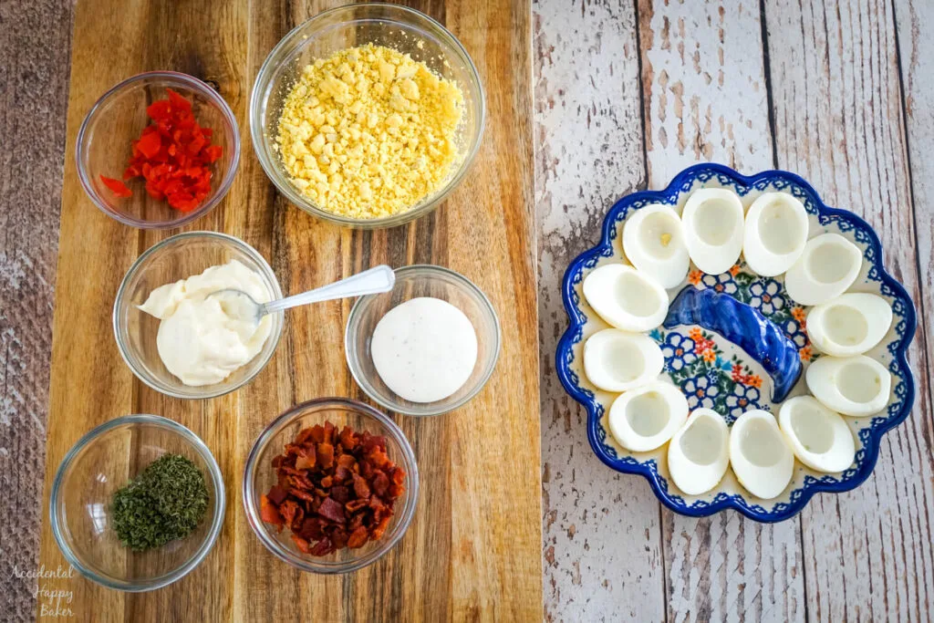 The ingredients needed for BLT deviled eggs: hard boiled eggs, tomatoes, mayo, ranch, chives, parsley, and bacon. 