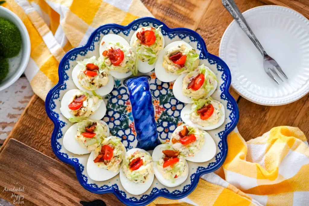 A plate of BLT deviled eggs on a wooden serving tray. 