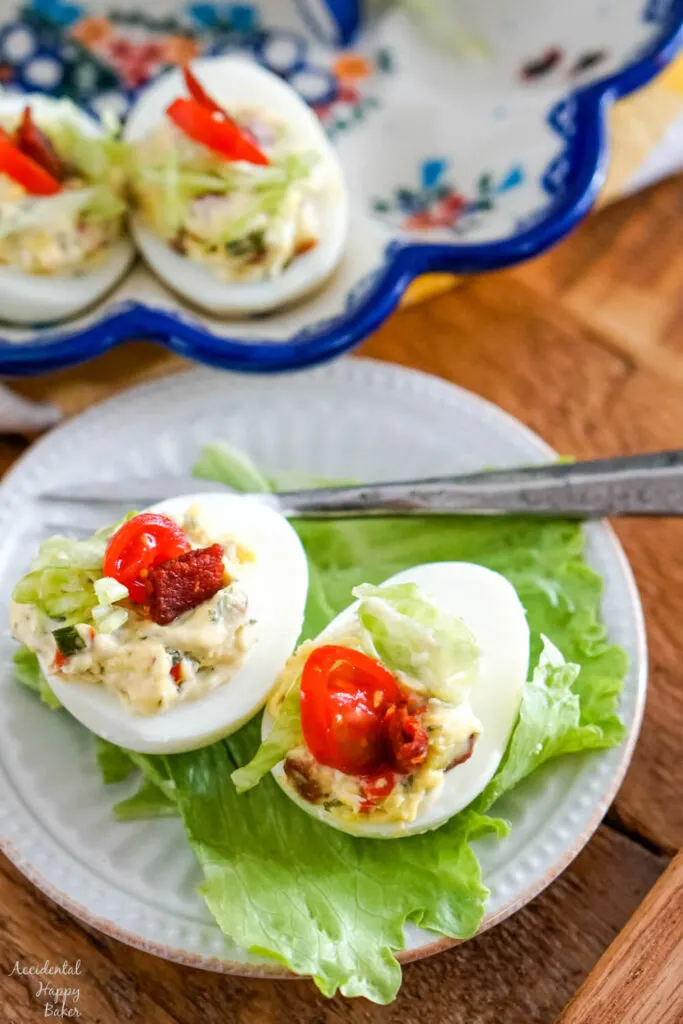 Two BLT deviled eggs on a bed of lettuce. 