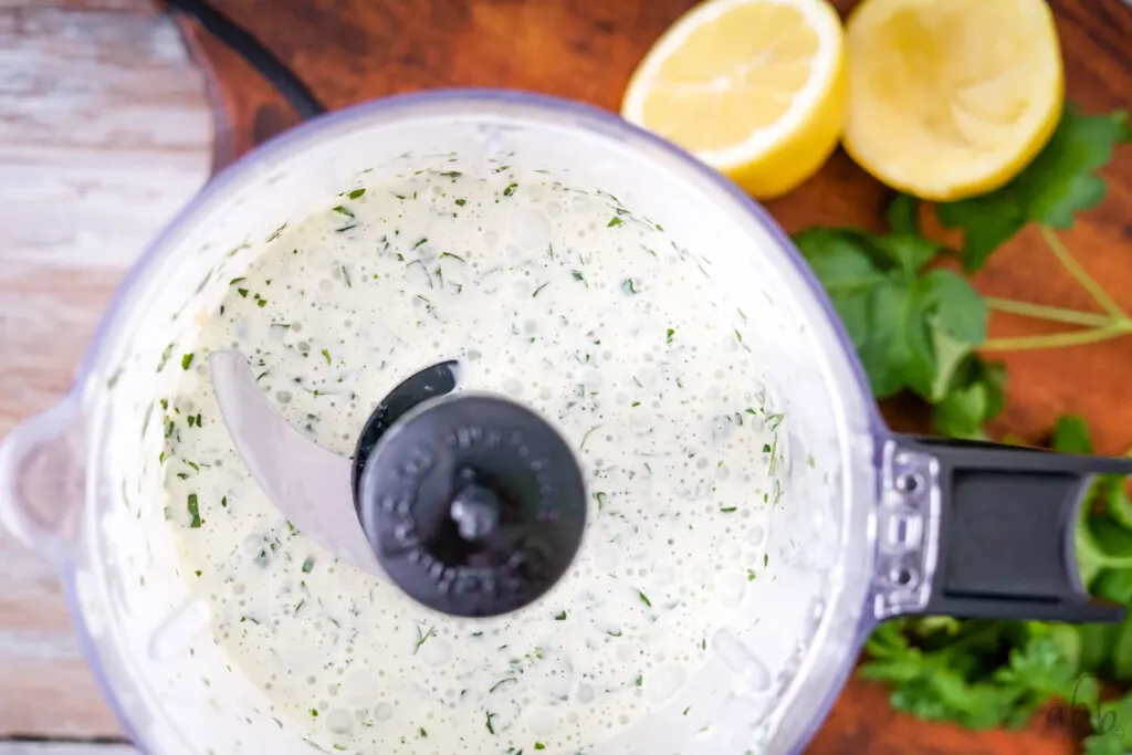 A food processor with the blended creamy herbed lemon dressing.