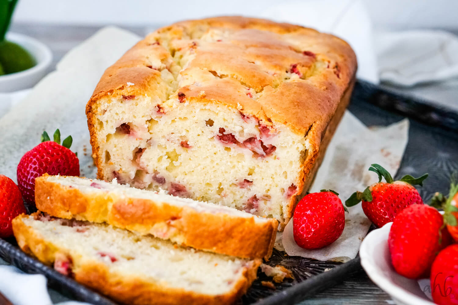 A sliced loaf of Strawberry Bread on a tray with fresh strawberries on each side. 