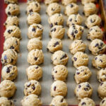 scoops of chocolate chip cookie dough portioned on a cookie sheet and ready to freeze.