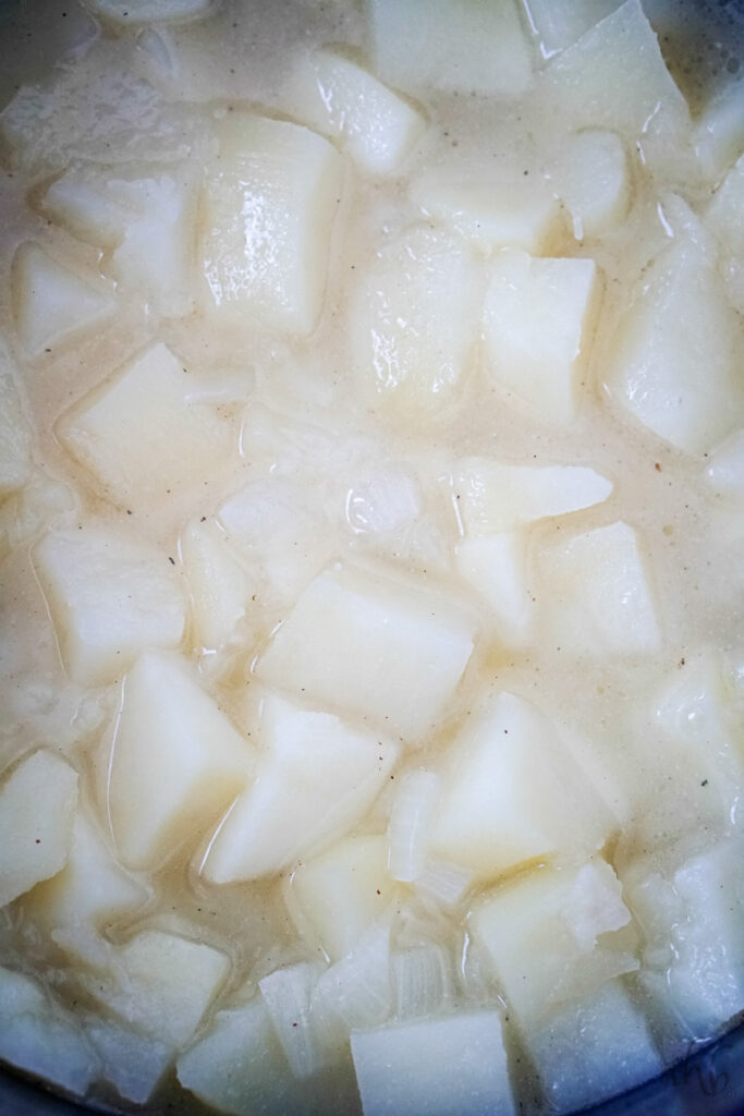 Potatoes and onions simmer in the stockpot until they are fork tender.